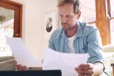 A man relaxed while dealing with mortgage debt or financial bankruptcy documents.