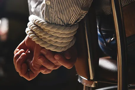 Hands of a person tied with rope.