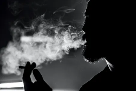 An image of a man exhaling smoke from a cigarette.