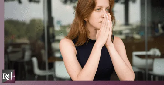 A girl who looks like she is praying while staring blankly.