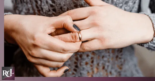 a woman holding her wedding ring and try to remove it