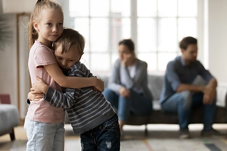 Upset little girl and boy, sister and brother hugging, suffering from parents problem.