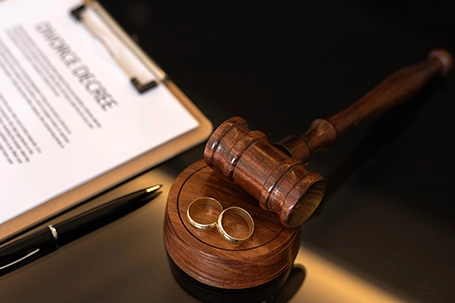 Divorce decree, gavel and wedding rings.