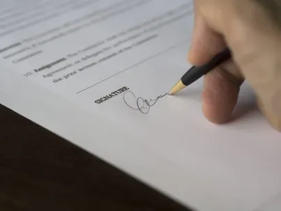 A hand signing a divorce paper.