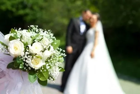 A wedding photo with a blurry background, featuring a bouquet of flowers in focus.