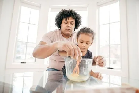 An image of a father and daughter cooking together.