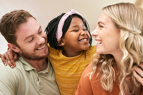 Family diversity and adoption with a foster mother, father and girl bonding in the living room of their home.