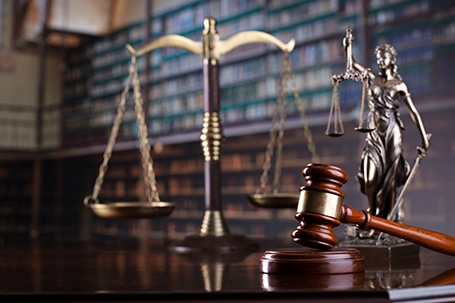 The scale and statue of justice, and judge's gavel on library background.