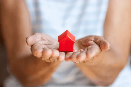 A red model house placed on an open hand.