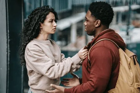 A man and a woman are facing each other, with the woman holding the man's jacket and looking straight into his eyes.