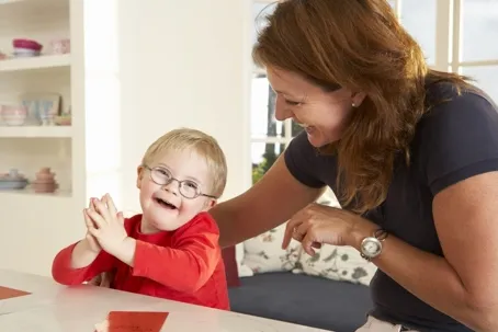 A mother and child laughing together while the mother smiles and talking to the baby