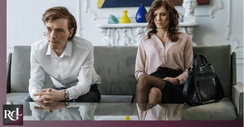 A couple sitting on a couch, not talking to each other, and seeming to have a problem.