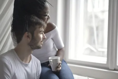An image of a sweet couple looking out the window in a clean white background