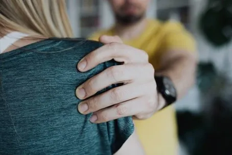 A man firmly holding a woman’s shoulder.