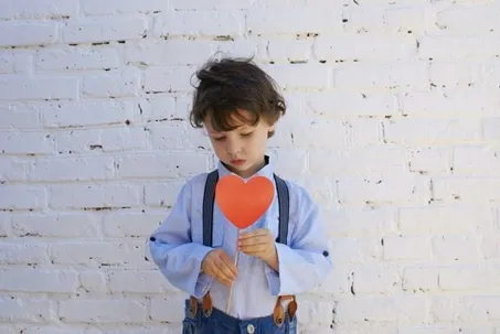 An image of a boy holding a heart against a white background.