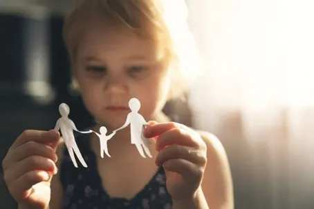 A young girl gazing at an illustration of her family on paper.