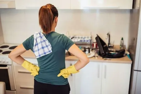 A woman standing in the kitchen, ready to start cleaning.