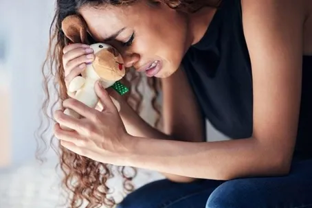 A woman crying as she holds a toy.
