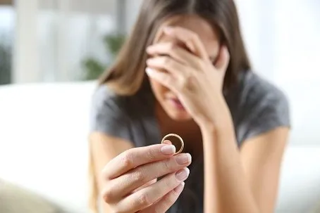 A single sad wife after divorce lamenting holding the wedding ring.