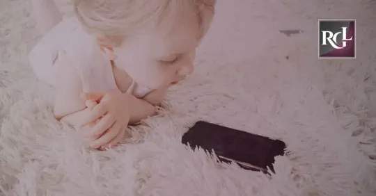 A little girl lying on the bed while looking at her cellphone, waiting for someone to call her.