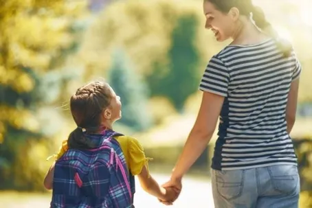 A joyful image of a mother and daughter holding hands while walking, with a blurred background
