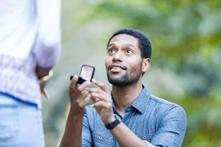 A man kneeling and proposing to his girlfriend.