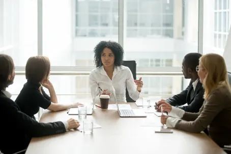 A woman is conducting a meeting with four other women
