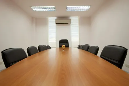"An image of a meeting room with a long table and several chairs.