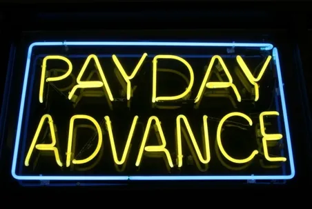 A neon sign that reads “PAYDAY ADVANCE” in yellow letters with a blue border.