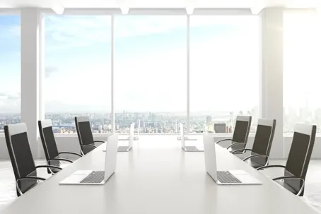 A clean table and chairs with a laptop on the table in an office.