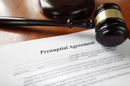 A wooden gavel and a prenuptial agreement are on the table.
