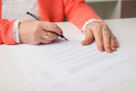 A close-up image of a woman signing a document.