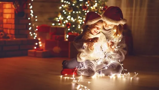 A mother and daughter holding Christmas lights.