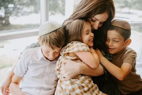 A mother hugs her three children.